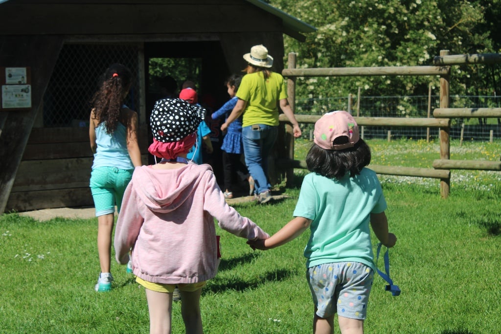 Two young campers holding hands walking towards the activity barn at L'Envol, the SeriousFun camp in France
