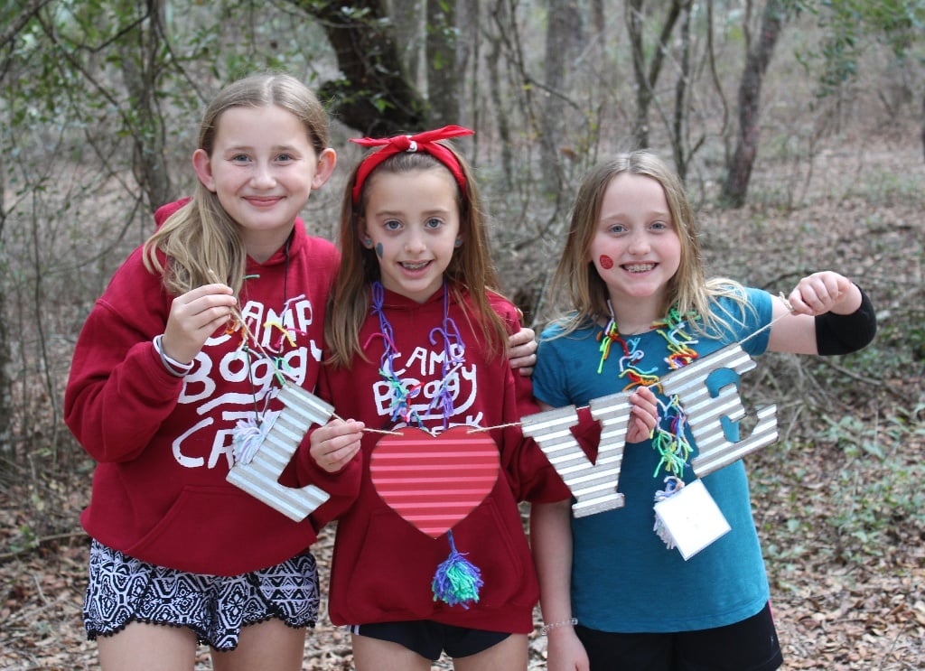 Three campers holding letters to spell LOVE at Camp Boggy Creek, the SeriousFun camp in Florida
