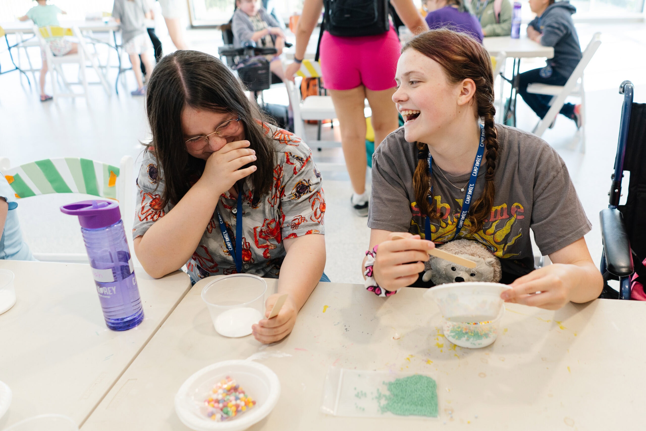 Deliah giggling in response to the friend sitting next to her at the craft table.