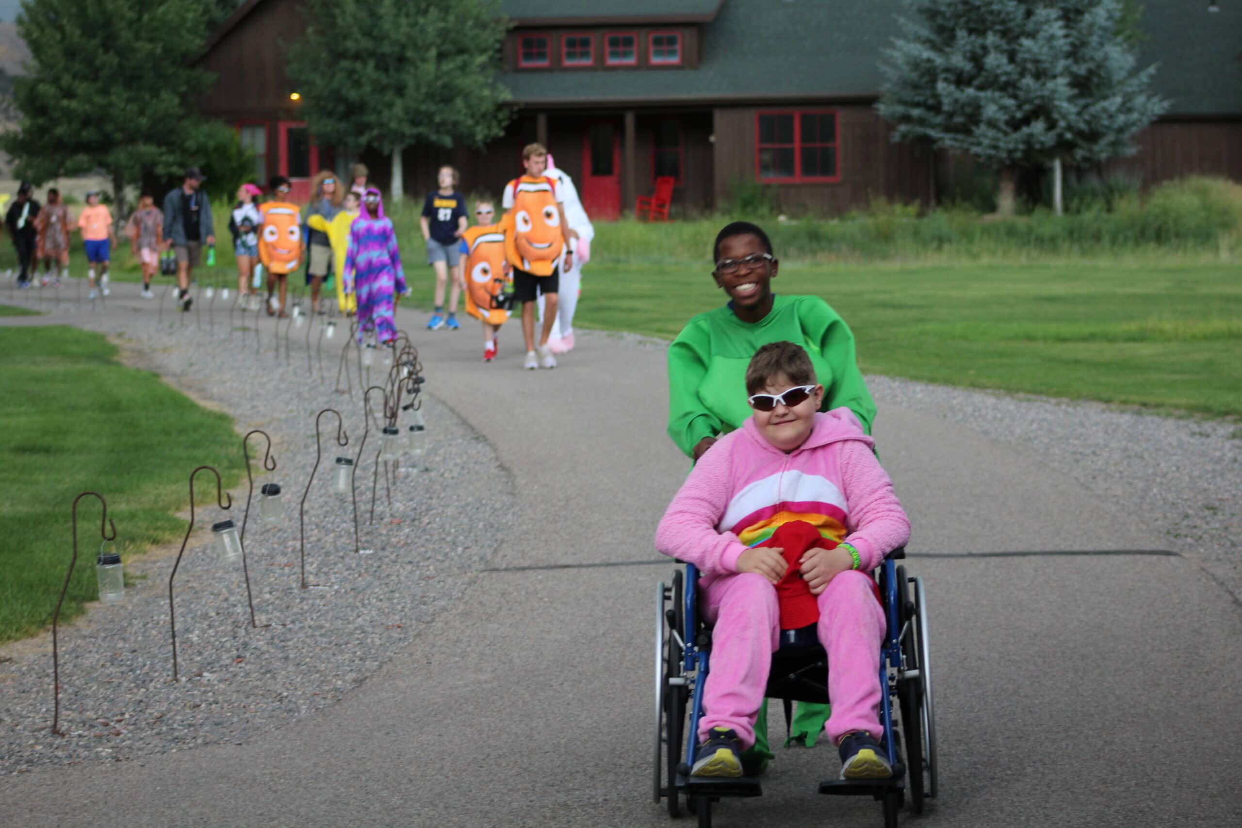 Counselor pushing the wheelchair of a smiling camper at camp